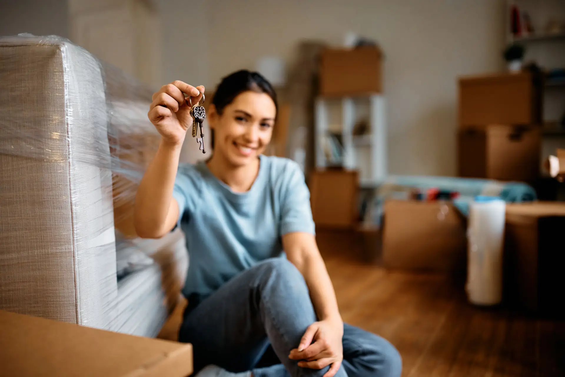 Woman holding a key while unpacking furniture in her new California home, symbolizing why to choose Mike Wright as your mortgage broker
